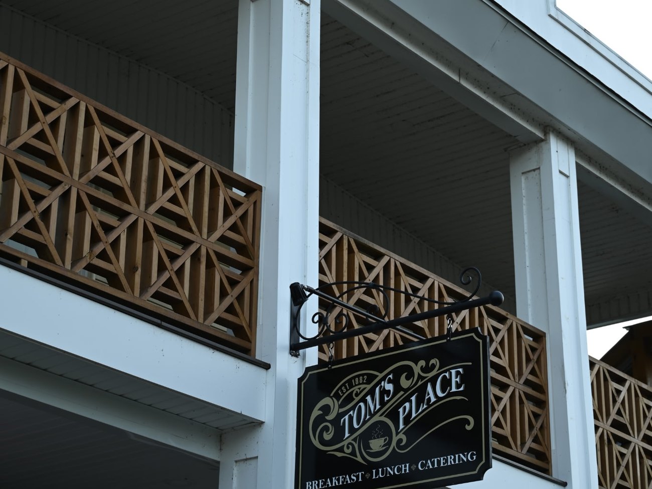 The hanging Tom's Place sign on the 1908 building