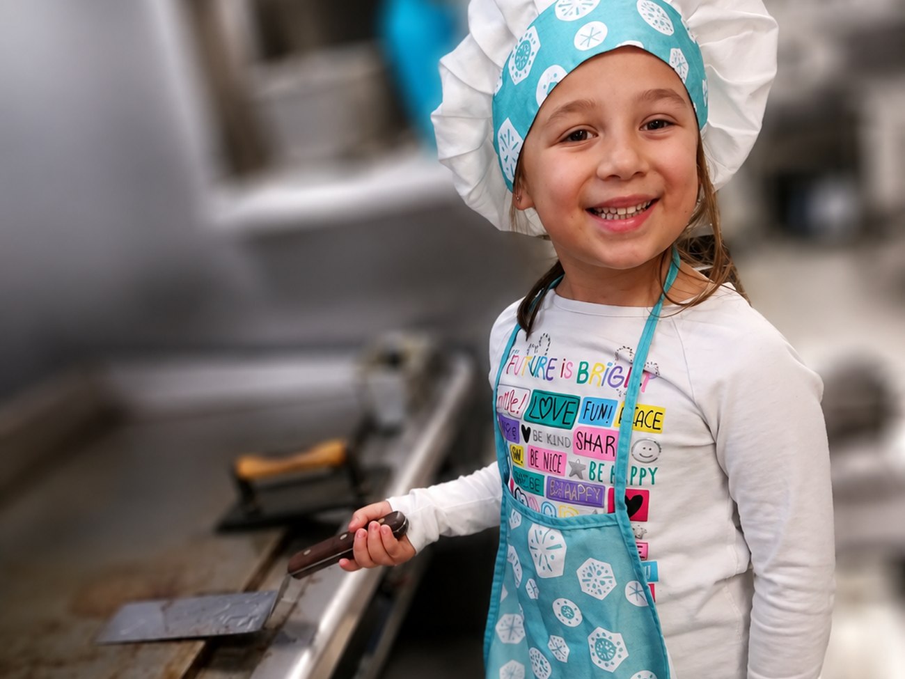 A young helper in a chef's hat at the griddle